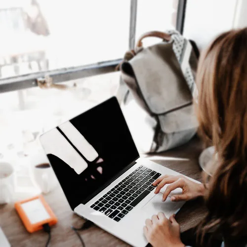 A woman users her laptop in a cafe - but someone is peerin gover her shoulder at her screen. MNK